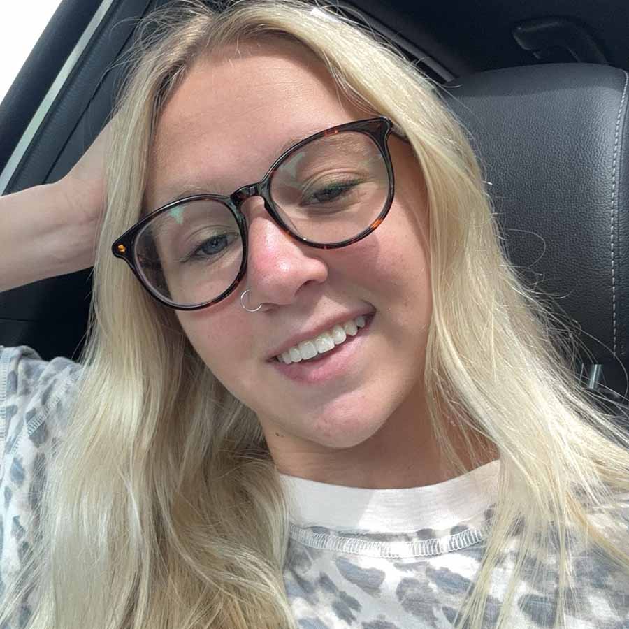 Woman with long blonde hair and glasses smiling in a car after visiting The Dirty Turtle Bar.