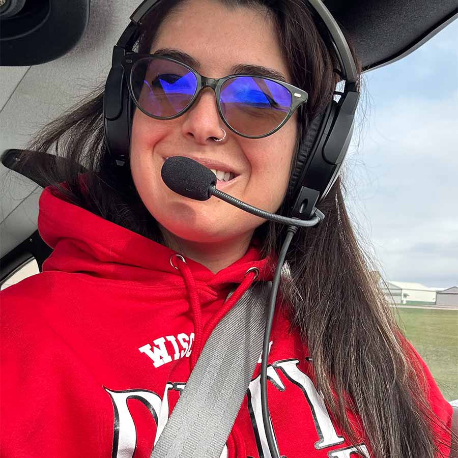 Smiling person in sunglasses and headset, repping The Dirty Turtle Bar in an aircraft cockpit.