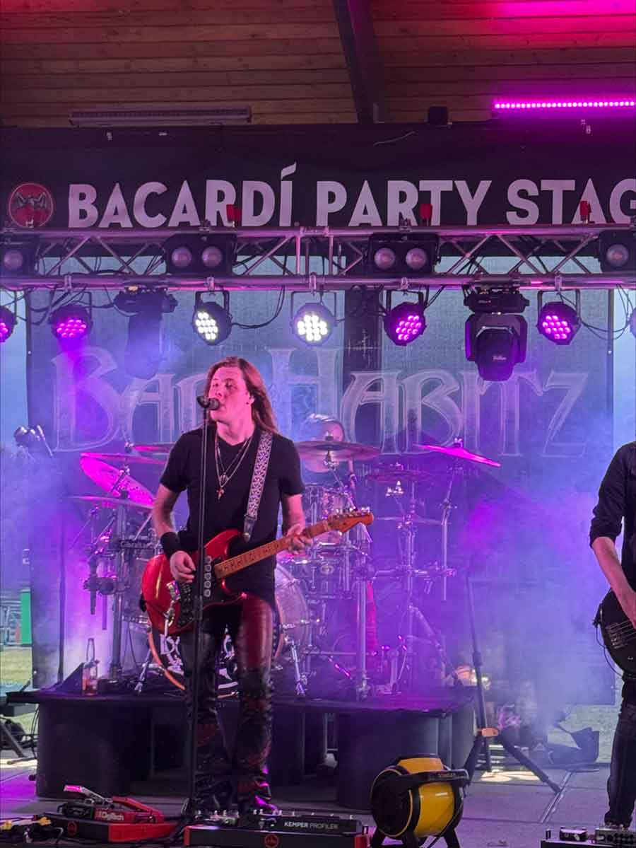 Guitarist sings onstage near The Dirty Turtle Bar and drinks, under purple Bacardí Party Stage lights.
