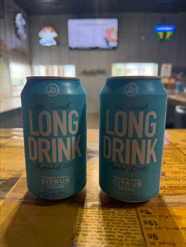 Two blue cans of The Finnish Long Drink on a wooden bar at The Dirty Turtle Bar.
